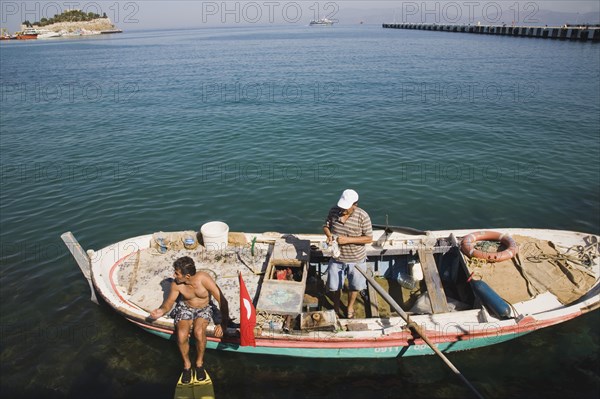 Kusadasi, Aydin Province, Turkey. Local fisherman in fishing boat with family member preparing to dive for mussels. Turkey Turkish Eurasia Eurasian Europe Asia Turkiye Aaydin Province Kusadasi Fishing Fisherman Fishermen Boat Dive Diver Diving Mussels Men Man Male Water Sea Destination Destinations European Male Man Guy Male Men Guy Middle East South Eastern Europe Water Western Asia