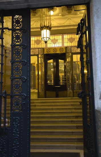 Budapest, Pest County, Hungary. Art Nouveau apartment building entrance. Hungarian Europe European East Eastern Buda Pest Budapest City Art Nouveau Apartment Building Entrance Hall Door Doorway Architecture Detail Steps Light Lamp Night Illuminated Ornate Destination Destinations Eastern Europe Flat Nite