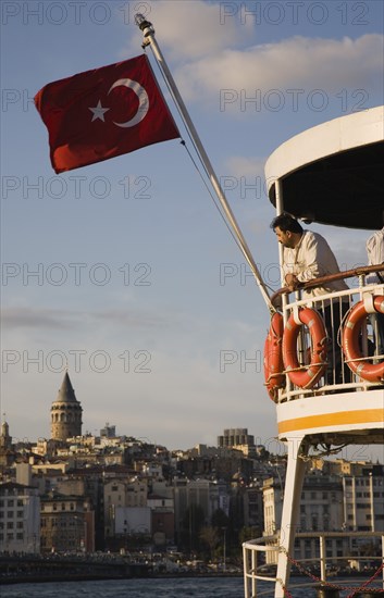 Istanbul, Turkey. Sultanahmet. Part view of passenger ferry flying Turkish flag with man leaning on railings of upper deck. Since March 2006 Istanbuls traditional commuter ferries have been operated by Istanbul Sea Buses. Turkey Turkish Istanbul Constantinople Stamboul Stambul City Europe European Asia Asian East West Urban Sultanahmet Bosphorous Destination Travel Tourism Transport Water Ship Boat Ferry Commuter Cummuters Classic Classical Destination Destinations Historical Male Men Guy Middle East Older One individual Solo Lone Solitary South Eastern Europe Turkiye Water Western Asia