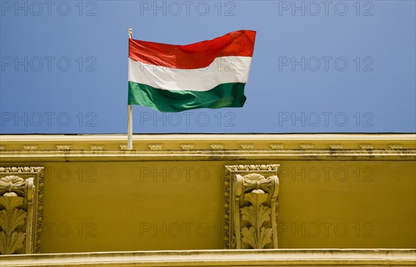Budapest, Pest County, Hungary. Hungarian flag flying from top of partly seen renovated building on Pest bank of the River Danube. Hungary Hungarian Europe European East Eastern Buda Pest Budapest City Architecture Flag Tricolor Tricolour Green White Red Blue Sky Detail Destination Destinations Eastern Europe