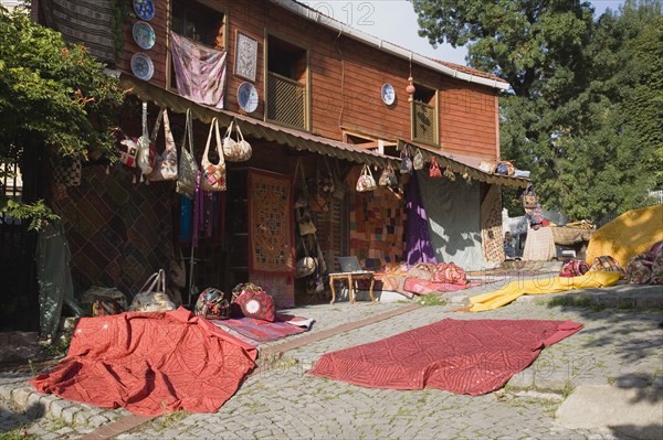 Istanbul, Turkey. Sultanahmet. Textiles and souvenirs displayed for sale next to Hagia Sophia. Turkey Turkish Istanbul Constantinople Stamboul Stambul City Europe European Asia Asian East West Urban Destination Travel Tourism Sultanahmet Textiles Cloth Display Displayed MArket Shop Store For Sale Red Destination Destinations Middle East South Eastern Europe Turkiye Western Asia