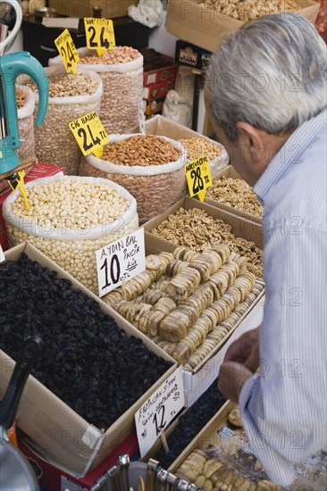 Istanbul, Turkey. Sultanahmet. The Spice Bazaar or Egyptian Bazaar one of the oldest bazaars in the city and the second largest covered shopping complex after the Grand Bazaar. Shopkeeper prepares display of dried fruit and nuts. Turkey Turkish Istanbul Constantinople Stamboul Stambul City Europe European Asia Asian East West Urban Destination Travel Tourism Sultanahmet Spice Bazaar Market Shop Store Stall Fruit Nuts Dried Food Goods 1 Destination Destinations Middle East One individual Solo Lone Solitary Shops Shoppers Mall Retail Buy Buying Market Markets Single unitary South Eastern Europe Turkiye Western Asia