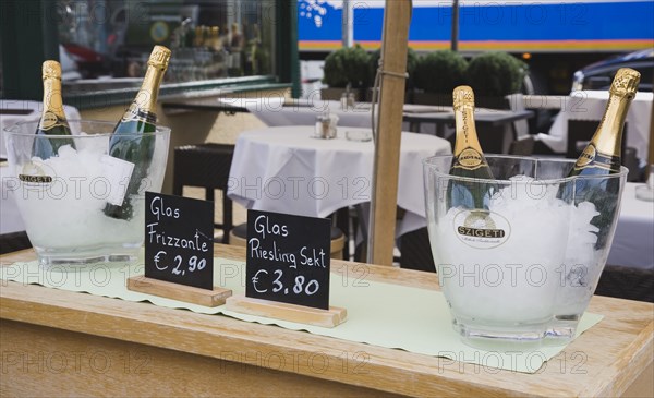 Vienna, Austria. The Naschmarkt Ice buckets with bottles of sparkling Riesling on side table in upmarket outdoor restaurant. Austria Austrian Republic Vienna Viennese Wien Europe European City Capital Naschmarkt Market Cafe Restaurant Bottle Buckets Ice Sparkling Wine Reisling Tables Alcohol Bar Bistro Destination Destinations Osterreich Viena Vino Vin Alcohol Grape Winery Drink Western Europe