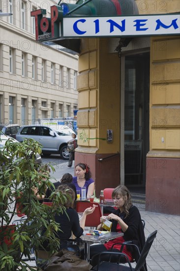 Vienna, Austria. People seated at Cafe tables on pavement outside cinema. Austria Austrian Republic Vienna Viennese Wien Europe European City Capital Cinema Exterior Cafe Outdoor People Tables Pavement Sidewalk Bar Bistro Destination Destinations Osterreich Restaurant Viena Western Europe