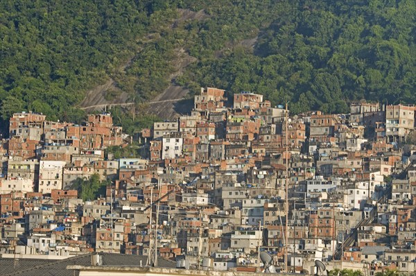 Rio de Janeiro, Brazil. Favela or slum on hillside above Copacabana neighbourhood steep road through slum rock face and tree cover with antenna in foreground. Brazil Brasil Brazilian Brasilian South America Latin Latino American City Urban Architecture Houses Housing Homes Copacabana Neighborhood Neighbourhood Favela Favelas Slum Slums Church Rio de Janeiro Aerial Destination Destinations Latin America Shanty South America Southern