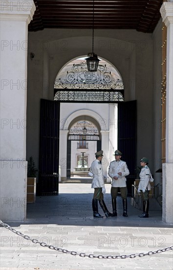 Santiago, Chile. Main entrance of the Palacio de la Moneda Presidential Palace guarded by high booted carabineros police a chain prevents tourists and onlookers from getting too close. Chile Chilean South America American Hispanic Santiago City Cityscape Urban Palacio de la Moneda Presidential Palace Guards Guard Guarded Security Poilce Policemen Policewoman Uniformed Carabineros Entrance Destination Destinations Holidaymakers Latin America Latino South America Southern Tourism