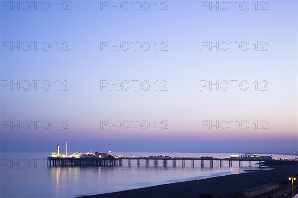 Brighton, East Sussex, England. View of the pier at sunset from the seafront promenade in Kemptown. England English UK United Kingdom United Kingdom GB Great Great Britain Britain British Europe European East Sussex East Sussex County Brighton Kemptown Marine Parade Sea Seafront Promenade Pier Sunet Blue Sky Illuminated Lit up Travel Silhouette Silhouetted