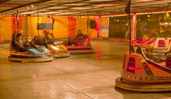 Lancing, West Sussex, England. Entertainment Funfairs Rides Dodgems illuminated at night. England English UK United Kingdom GB Great Britain British Europe European West Sussex Lancing Funfair Rides Night Entertainment Leisure Color Colour Colorful Colourful Colored Coloured People Crowd Blur Blurred Dodgem Dodgems Bumber Car Cars Electrified Electric Metal Floor Gauze Ceiling