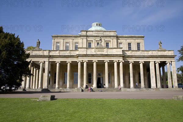 Cheltenham, Gloucestershire, England. The Regency Pittville Pump Room spa building. England English UK United Kingdom GB Great Britain British Gloucestershire Cheltenham County Town Spa Europe European Architecture Facade Exterior Regency Pump Room Pittville Park Entrance Cotswold Cotswolds Water Waters Blue British Isles Destination Destinations Great Britain History Historic Northern Europe United Kingdom