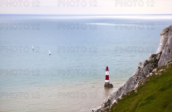 Eastbourne, East Sussex, England. Beachy Head view of the lighthouse at the base of the chalk cliffs. England English UK United Kingdom GB Great Britain Birtish East Sussex County Eastbourne Beachy Head Sea Coast Chalk Cliff Cliffs White Lighthouse Light House Boat Ship Transport Warning