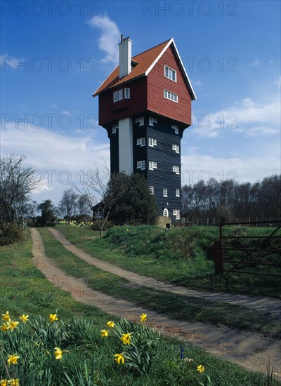 Thorpeness, Suffolk, England. Converted former water tower the House in the Clouds with daffodils growing beside footpath in the foreground. European Great Britain Northern Europe UK United Kingdom White
