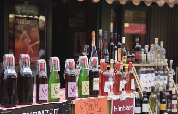 Vienna, Austria. The Naschmarkt. Display of Federweisser wine in the fermentation stage known as Sturm in Austria line of bottles with tasting glasses. Due to the carbonic acid Federweier tastes quite refreshing not unlike a grape lemonade or a sweet sparkling wine. Austria Austrian Republic Vienna Viennese Wien Europe European City Capital Naschmarkt Market Drink Drinks Alcohol Wine Fermentation Fermentation Sturm Display Bottles Destination Destinations Osterreich Viena Vino Vin Alcohol Grape Winery Drink Western Europe