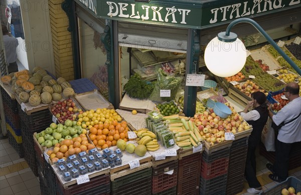 Budapest, Pest County, Hungary. Looking down on stall selling fruit and vegetables at Nagy Vasarcsarnok the Central Market. Hungary Hungarian Europe European East Eastern Buda Pest Budapest City Nagy Vasarcsarnok Central Market markets Fruit Veg Vegetable Vegetables Stall Shop Store People Destination Destinations Eastern Europe