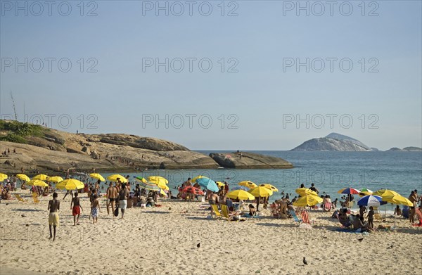 Rio de Janeiro, Brazil. Arpoador end of Ipanema beach with yellow umbrellas blue sea and sky swimmers in sea and on rocks and pigeons on beach. Brazil Brasil Brazilian Brasilian South America Latin Latino American City Travel Destination Urban Vacation Beach Beaches People Sunbathing Crowds Umbrellas Parasols Swimmers Swimming Arpoador Ipanema Destination Destinations Holidaymakers Latin America Sand Sandy Beach Tourism Seaside Shore Tourist Tourists Vacation Sand Sandy Beaches Tourism Seaside Shore Tourist Tourists Vacation South America Southern Sunbather Water