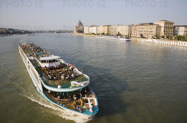 Budapest, Pest County, Hungary. Pleasure cruise boat on the River Danube approaching Szechenyi Chain Bridge or Memory Bridge with Hungarian Parliament Building behind on right on Pest bank. Hungary Hungarian Europe European East Eastern Buda Pest Budapest City River Danube Cruise Ship Boat Ferry Tourist Tourists Travel Transport Holiday Vacation Parliament Building Cityscape Water Destination Destinations Eastern Europe Holidaymakers Parliment Sightseeing Tourism