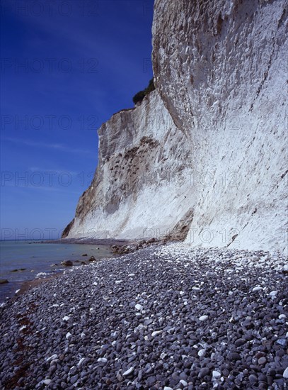 Denmark, Isle of Mon, Mons Klint, East facing chalk sea cliffs rising from flintstone beach.  Blue sky with high windswept clouds above.