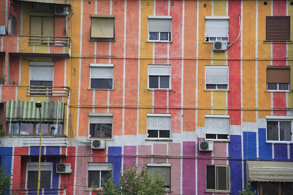 Albania, Tirane, Tirana, Detail of exterior facade of apartment block painted in stripes of different colours with multiple windows and balconies.