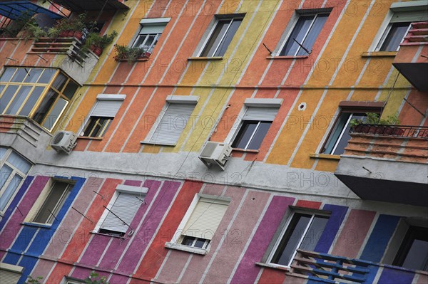 Albania, Tirane, Tirana, Angled part view of exterior facade of apartment block painted in brightly coloured stripes with multiple windows and balconies.