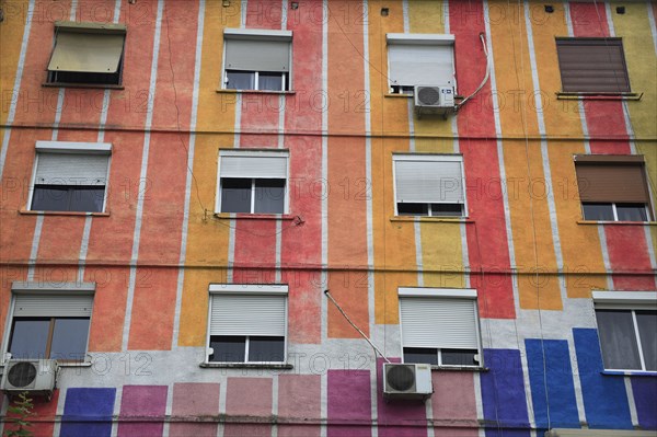 Albania, Tirane, Tirana, Part view of exterior facade of apartment block painted in stripes of different colours  with multiple windows.