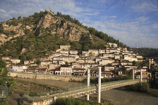 Albania, Berat, Traditional Ottoman buildings across hillside overlooking footbridge over the River Osum.