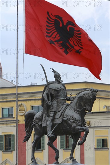 Albania, Tirane, Tirana, National flag depicting two headed eagle flying above equestrian statue of George Castriot Skanderbeg  the national hero of Albania.