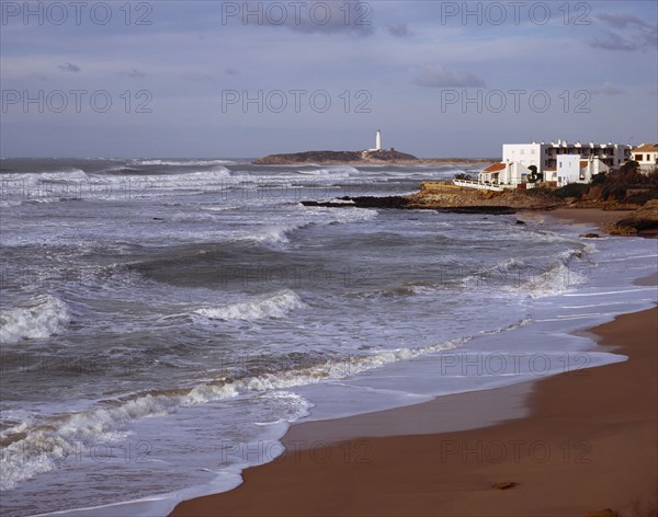 Spain, Andalucia, Cadiz, Cape Trafalgar and Los Canos de Meca village apartments overlooking beach with surf breaking on the sand.