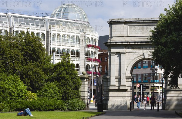 Ireland, County Dublin, Dublin City, Saint Stephens Green shopping arcade and Fusiliers Arch entrance into the park with people.