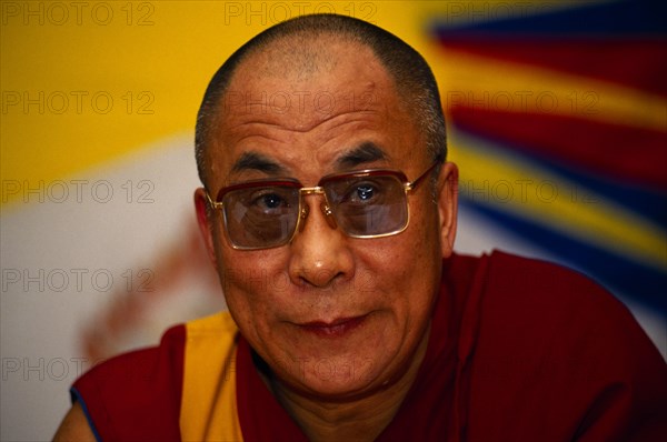 China, Tibet, Buddhism, Portrait of the 14th Dalai Lama. Tibetan Buddhist Leader in exile. Vibrant image of a yellow sun in the background.