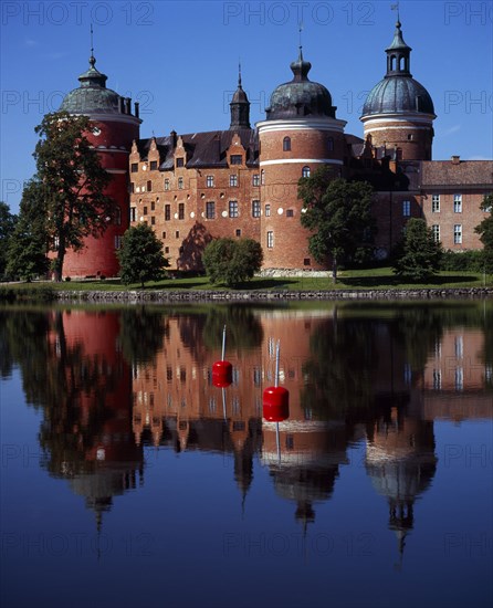 Sweden, Sodermanland, Mariefred, Gripsholm Castle beside Lake Malaren.  Red brick exterior with domed towers  dating from the sixteenth century  reflected in water.