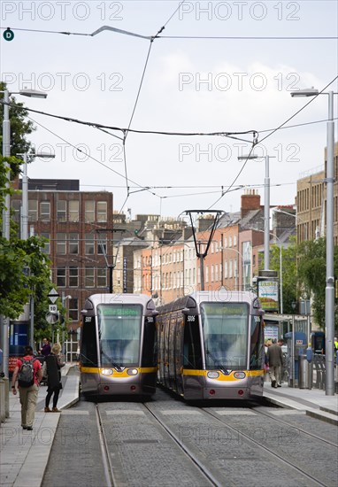 Ireland, County Dublin, Dublin City, Luas light rail trams at stop beside Saint Stephens Green with people.