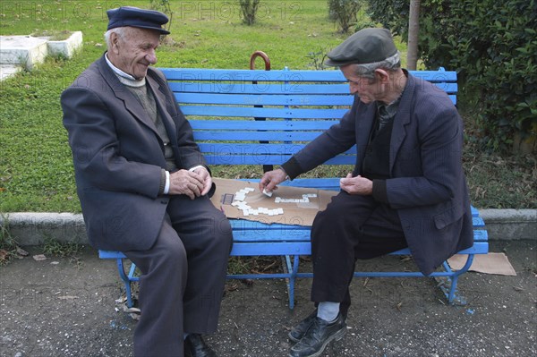 Albania, Berat, Two elderly men playing dominos on park bench.