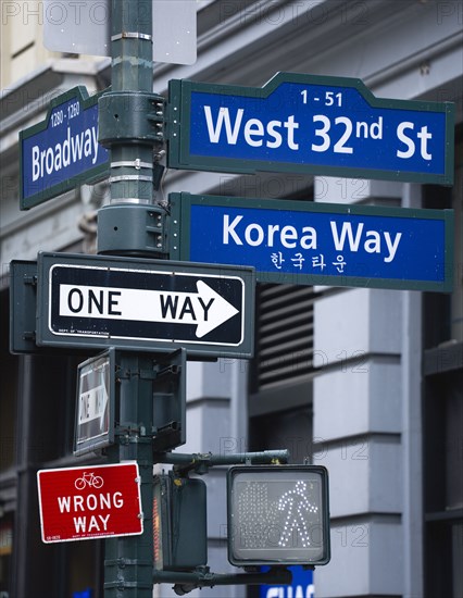 USA, New York, New York City, Manhattan  Street signs for West 32nd Street also known as Korea Way in Little Korea in Midtown with pedestrian crossing light and cycle lane wrong way sign in red and One Way sign.