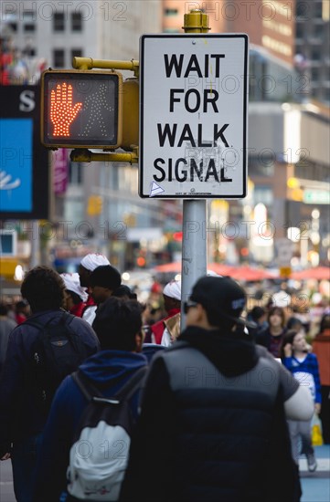 USA, New York, New York City, Manhattan  People in Times Square by pedestrian crossing sign with a red hand illuminated to stop and do not cross beside a sign that says Wait For Walk Signal.