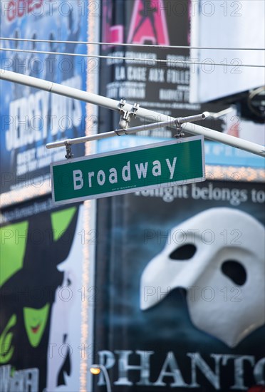 USA, New York, New York City, Manhattan  Overhead road sign for Broadway with theatre stage show posters or billboards on buildings beyond.