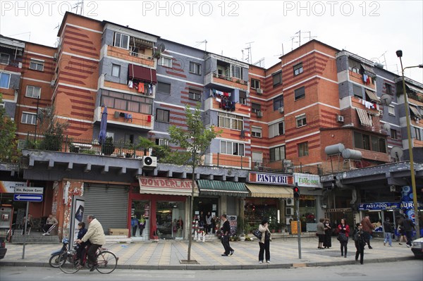 Albania, Tirane, Tirana, Colourful apartment buildings with washing hanging from balconies and shops and busy street below.