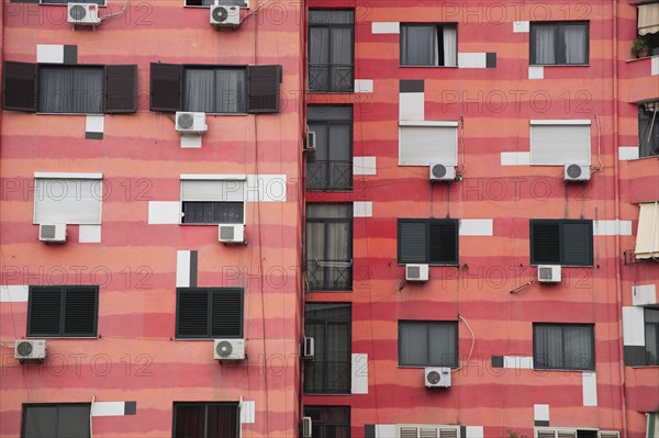 Albania, Tirane, Tirana, Part view of exterior facade of colourful apartment building with shuttered windows and air conditioning units.