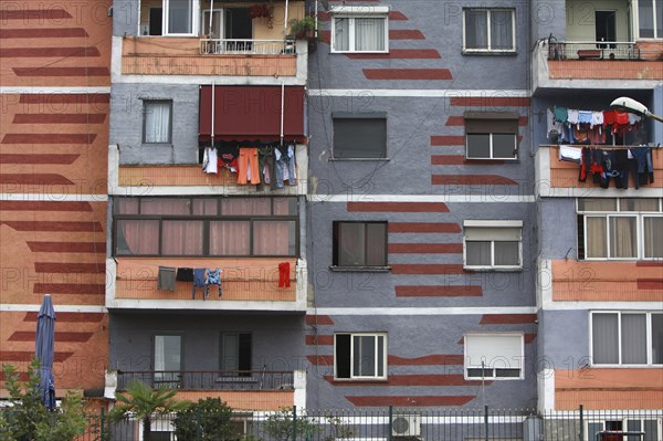 Albania, Tirane, Tirana, Part view of exterior facade of colourful apartment building with washing hanging on the balconies.