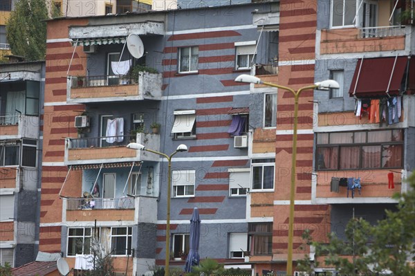 Albania, Tirane, Tirana, Part view of exterior facade of colourful apartment building with washing hanging on the balconies.