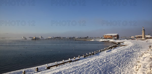 England, West Sussex, Shoreham-by-Sea , Mist rising from harbour waters on frosty morning with snow on the beach.