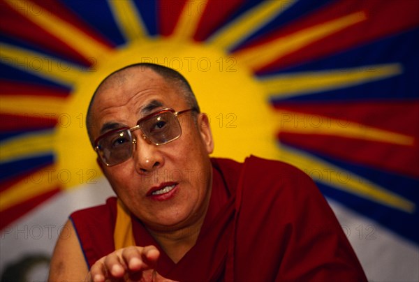 China, Tibet, Buddhism, The 14th Dalai Lama speaking to followers. Vibrant image of a yellow sun in the background.