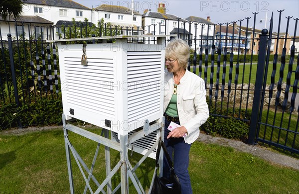 Climate, Weather, Measurements, Female observer beside a Stevensons screen cabinet which holds various thermometers for measuring minimum and maximum temperatures and relative humidity at the Bognor Regis weather station.