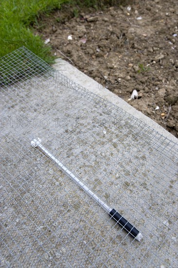 Climate, Weather, Measurements, Thermometer beneath protective wire mesh laid on concrete to measure the minimum overnight concrete temperature beside patch of clear earth where the moisture content of the earth is observed at the Bognor Regis weather sta