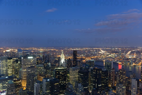 USA, New York, New York City, Manhattan  View from Empire State building over midtown skyscrapers and East River towards Queens and Long Island with Art Deco Chrysler Building illuminated at sunset.