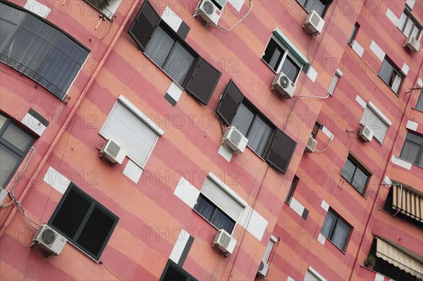 Albania, Tirane, Tirana, Angled part view of exterior facade of colourful apartment building with shuttered windows and air conditioning units.