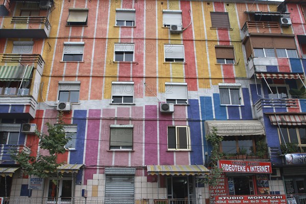 Albania, Tirane, Tirana, Exterior facade of striped  multi-coloured apartment block with windows  window blinds and air conditioning units.