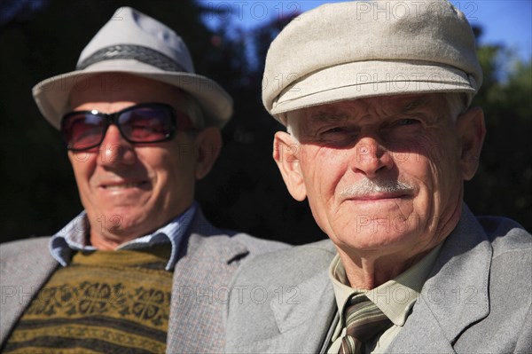 Albania, Tirane, Tirana, Head and shoulders portrait of two men. One elderly looking straight to camera  one wearing sun-glasses slightly behind  both wearing hats.