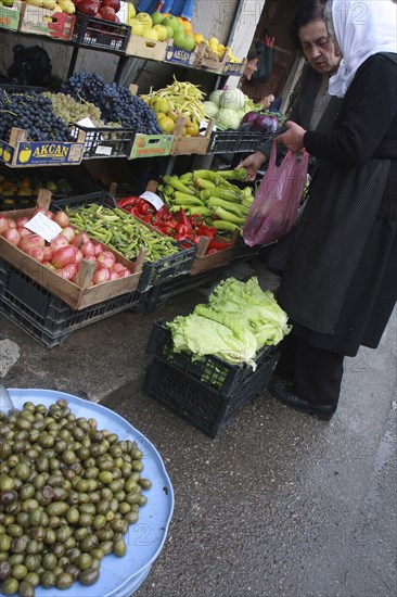 Albania, Tirane, Tirana, Female customers at fruit and vegetable stall in the Avni Rustemi market  selecting from display including grapes  peppers and lettuce.