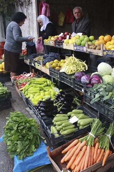 Albania, Tirane, Tirana, Customers and vendor beside display of fruit and vegetables at grocers in the Avni Rustemi market.