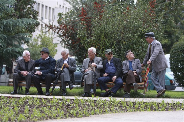 Albania, Tirane, Tirana, Group of elderly men and pensioners talking on a park bench.