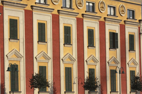 Albania, Tirane, Tirana, Detail of red and yellow exterior facade of government buildings on Skanderbeg Square.